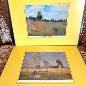 May include: Two yellow placemats with blue edging. Each placemat has a framed print of a Claude Monet painting. One print depicts a field of red poppies, the other a woman in a field.
