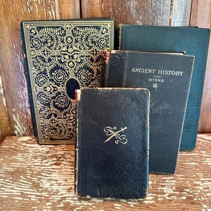 Puede incluir: Cuatro libros antiguos con cubiertas de cuero negro. El libro de arriba tiene el t&iacute;tulo "Ancient History" con el autor "Myers" impreso en el lomo. El libro de abajo tiene un dise&ntilde;o dorado de espadas cruzadas.