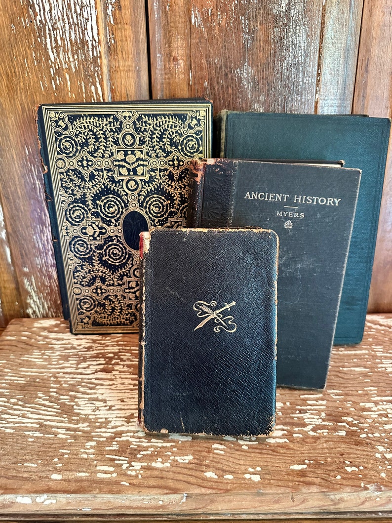 Puede incluir: Cuatro libros antiguos con cubiertas de cuero negro. El libro de arriba tiene el t&iacute;tulo "Ancient History" con el autor "Myers" impreso en el lomo. El libro de abajo tiene un dise&ntilde;o dorado de espadas cruzadas.