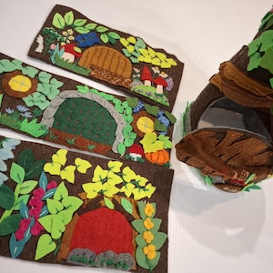 May include: Four felt pieces with different woodland scenes, each featuring a small door, and a felt tree trunk with a door and green leaves.