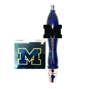 May include: Blue and gold University of Michigan logo on a black background.  The logo is on a sticker that says "Aluminum,  Vinyl & Adhesive Backing".  The sticker is next to a blue and silver beer tap handle.