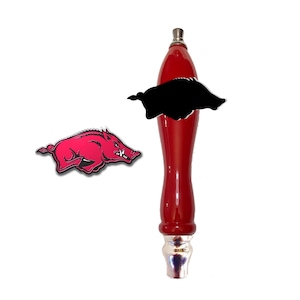 May include: Red beer tap handle with a silver base and a black and white image of a running pig.