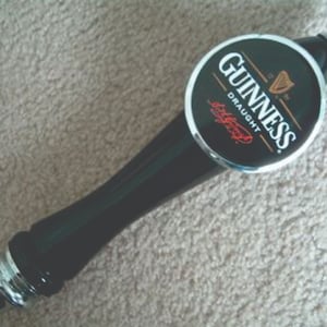 May include: A black and silver Guinness draught beer tap handle with a black and white logo that says "Guinness Draught"