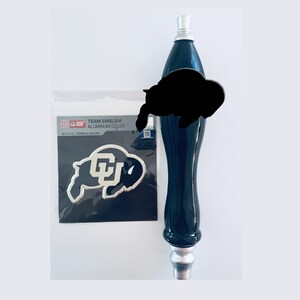 May include: A black and silver beer tap handle with a University of Colorado Buffaloes logo sticker. The sticker is silver with a black buffalo silhouette and the letters CU in the center. The sticker says "Team Emblem Aluminum Color with Full Adhesive Backing".