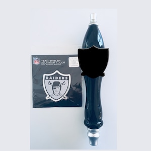 May include: Black and silver Raiders NFL team emblem sticker and a black and silver beer tap handle.