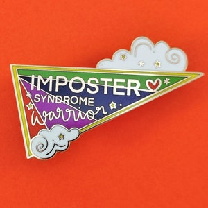 May include: A colorful enamel pin in the shape of a triangle with the words "IMPOSTER SYNDROME WARRIOR" in white lettering. The pin features a rainbow gradient, gold trim, and white cloud accents with stars. The background is orange.