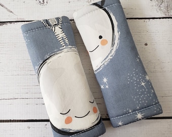 Könnte beinhalten: Zwei blaue Stoff-Reißverschluss-Zipper mit weißen Mond- und Stern-Designs. Ein Mond hat ein lächelndes Gesicht und der andere ein lächelndes Gesicht mit geschlossenem Auge.