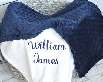 May include: A white and navy blue baby blanket with the name "William James" embroidered in navy blue.