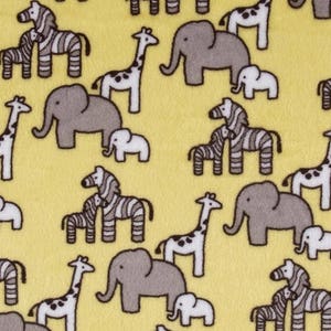 Puede incluir: Una tela amarilla con un patr&oacute;n repetido de cebras, elefantes y jirafas grises y blancas. Los animales est&aacute;n todos mirando en diferentes direcciones y est&aacute;n en varias poses.