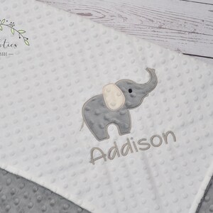 Puede incluir: Una manta de beb&eacute; blanca y gris con un elefante bordado gris y el nombre Addison.