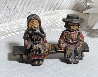 Pareja holandesa en miniatura sentada en un banco de hierro.