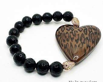 May include: A black beaded bracelet with a large heart-shaped charm. The charm has a brown and tan leopard print design. The bracelet is on a white background. The text "MY JEWELRY SHED" is in the bottom right corner.