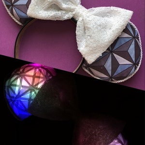 Op de afbeelding: Een paar witte pailletten Minnie Mouse oren met een geometrisch patroon op de oren. Het patroon is in tinten blauw, grijs en wit.