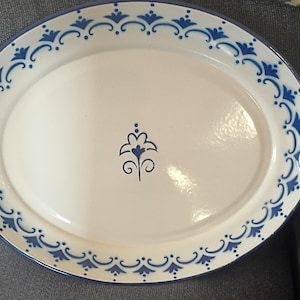 Puede incluir: Plato ovalado blanco con un borde floral azul y un diseño floral central. El plato tiene un borde azul y probablemente está hecho de cerámica o porcelana. Una pieza decorativa para servir alimentos.