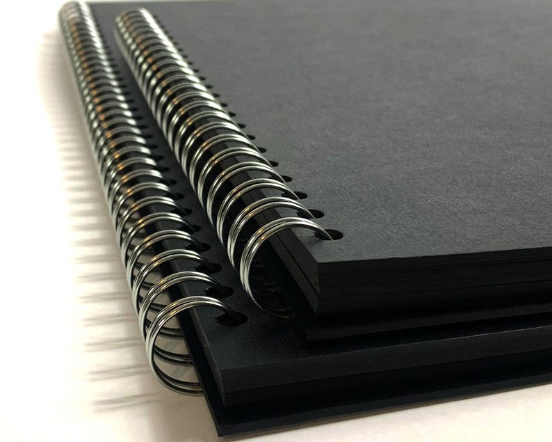 Puede incluir: Un cuaderno negro de espiral con una cubierta texturizada. El cuaderno est&aacute; cerrado y la encuadernaci&oacute;n es visible.
