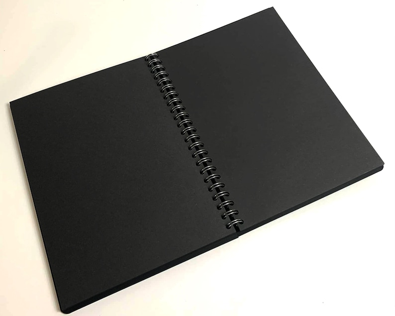 Puede incluir: Un cuaderno negro de espiral con una cubierta negra.