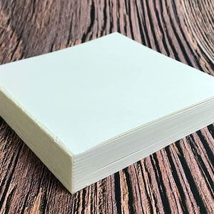 Op de afbeelding: Een stapel witte vellen papier, waarschijnlijk voor tekenen of schrijven, op een houten oppervlak.