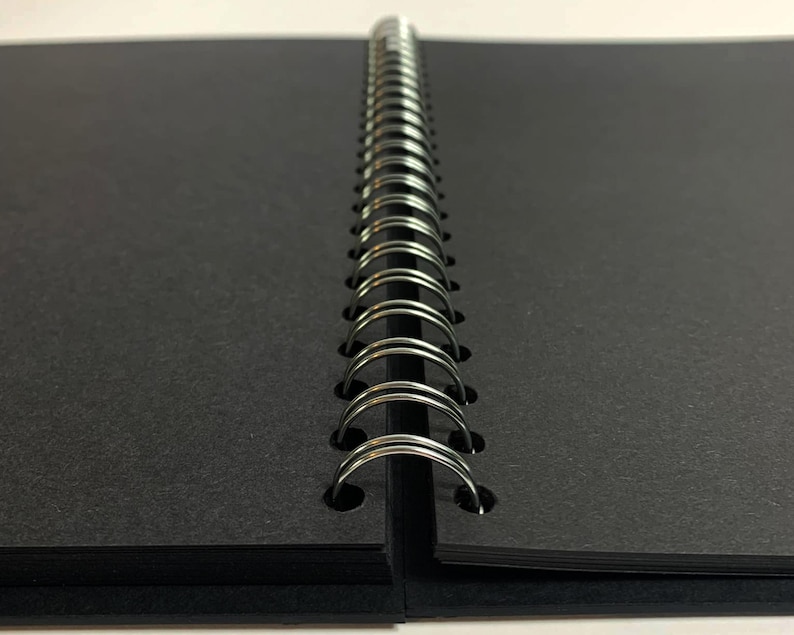 Puede incluir: Un cuaderno negro de espiral con una cubierta negra.