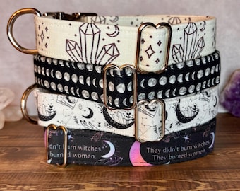 May include: A stack of four dog collars with gold-colored hardware. The collars feature various patterns, including crystals, moons, and the text "They didn't burn witches. They burned women." Colors include black, white, and purple.