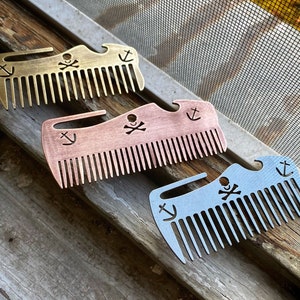 May include: Three metal pocket combs with a skull and crossbones design, a bottle opener, and an anchor. The combs are gold, copper, and silver.