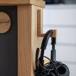 May include: A wooden organizer with a black chalkboard surface and a hook for headphones. The chalkboard has a round wooden plaque with the text "Lieblingsmensch" on it.