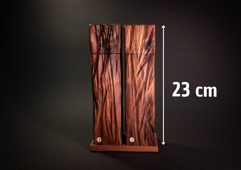 Op de afbeelding: Twee hoge, rechthoekige houten containers met een getextureerd, gesneden ontwerp. De donkerbruine containers staan op een kleine houten basis. De hoogte is 23 cm.