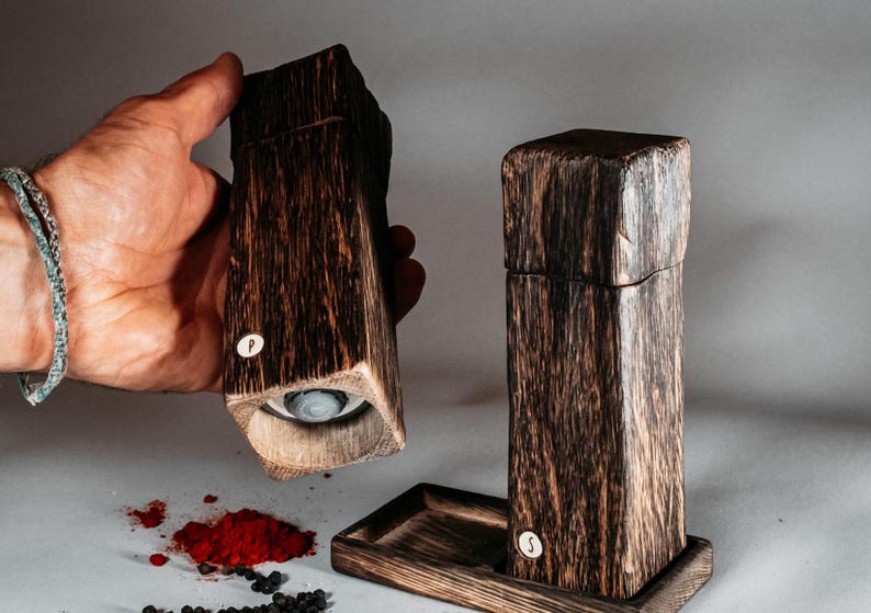 May include: Two wooden salt and pepper shakers with a dark brown finish. The shakers are labeled "S" and "P".