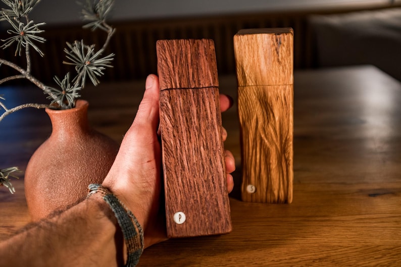 Peut inclure: Deux moulins &agrave; sel et &agrave; poivre en bois, l'un est brun fonc&eacute; avec un motif de grain de bois et l'autre est brun clair avec un motif de grain de bois. Les deux moulins ont un petit bouton en m&eacute;tal sur le dessus.