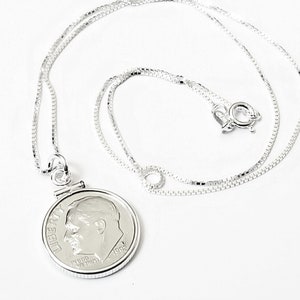 May include: A silver chain necklace with a silver dime pendant featuring the profile of Abraham Lincoln and the inscription "LIBERTY" and "IN GOD WE TRUST".