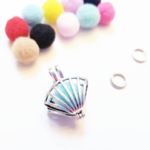 May include: A silver charm with a fan-shaped design and a light blue interior. The charm is a locket with a hinged lid. Two silver jump rings are also pictured.