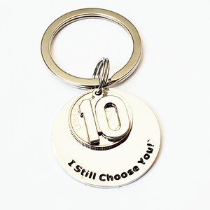 May include: Silver keychain with a round charm that says "I Still Choose You!" and a smaller charm with the number 10.