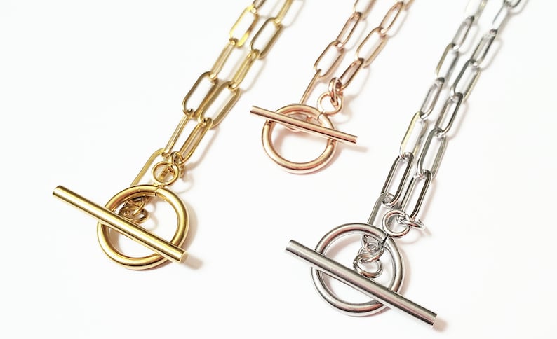 Puede incluir: Tres collares de oro, oro rosa y plata con cierres de palanca. Cada collar presenta una cadena hecha de eslabones ovalados unidos.