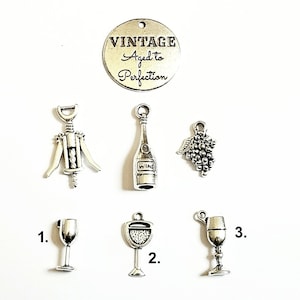 May include: Silver charm set with wine-themed charms, including a corkscrew, wine bottle, grapes, and three different wine glasses. The charm set also includes a round charm with the text "Vintage Aged to Perfection".