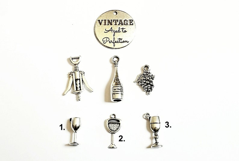 May include: Silver charm set with wine-themed charms, including a corkscrew, wine bottle, grapes, and three different wine glasses. The charm set also includes a round charm with the text "Vintage Aged to Perfection".