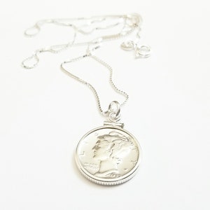 May include: A silver necklace with a silver coin pendant featuring the profile of a woman. The coin has the year 1920 inscribed on it.