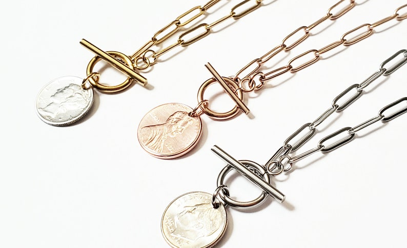 Puede incluir: Tres collares de oro, oro rosa y plata con un colgante de moneda y un cierre de palanca. Los colgantes de moneda presentan un perfil de una persona.