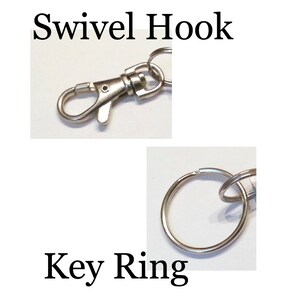 May include: A silver swivel hook attached to a silver key ring. The hook is open and ready to be attached to something.