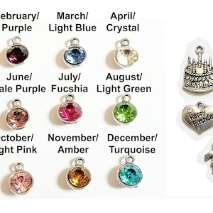 May include: A set of 12 birthstone charms, each with a different color crystal, representing the months of the year. There are also five charms with different designs, including a birthday cake, a heart with the words "Happy Anniversary", a heart with the words "Happy Birthday", a cupcake, and a gift box.