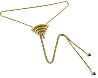May include: A gold chain necklace with a geometric pendant and black bead accents.