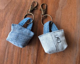 May include: Two denim keychain bags with metal key rings. One bag is blue denim and the other is light blue denim with the initials "LMD" embroidered on the front.