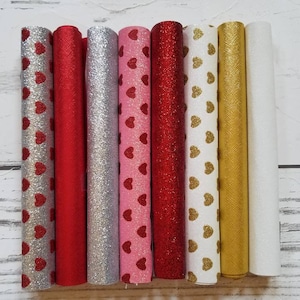 May include: Six rolls of glitter fabric with a heart pattern. The fabric rolls are in the colors red, silver, pink, red, white, and gold.