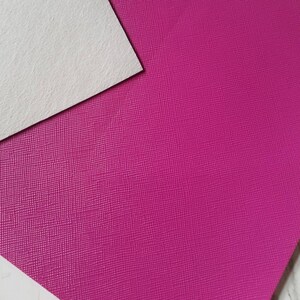 May include: A close-up of a textured, pink fabric. The fabric has a subtle, pebbled texture.