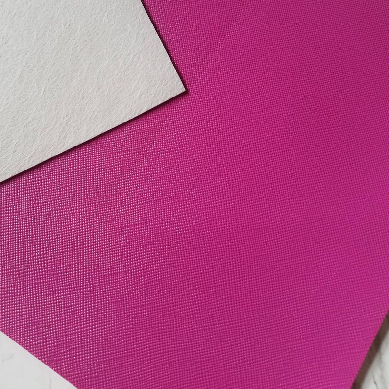 May include: A close-up of a textured, pink fabric. The fabric has a subtle, pebbled texture.