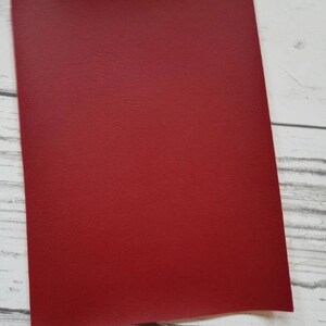 Puede incluir: Una hoja de cuero sint&eacute;tico rojo. El cuero tiene una superficie texturizada.