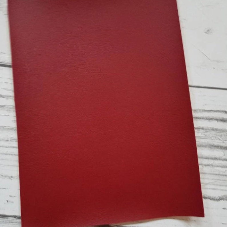 Puede incluir: Una hoja de cuero sint&eacute;tico rojo. El cuero tiene una superficie texturizada.