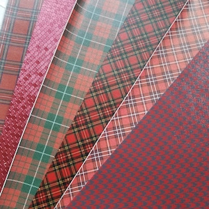 May include: A collection of red and burgundy patterned papers. The patterns include plaid, houndstooth, and textured designs. The papers are arranged diagonally, showcasing the variety of textures and colors.