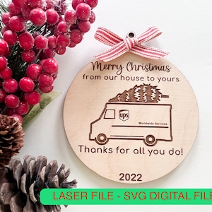 Könnte beinhalten: Ein runder Weihnachtsbaumschmuck aus Holz mit einem Laser-geschnittenen Design eines UPS-Lastwagens, der einen Weihnachtsbaum transportiert. Der Anhänger lautet "Frohe Weihnachten von unserem Haus zu Ihrem" und "Danke für alles, was Sie tun!" mit dem Jahr 2022 unten.
