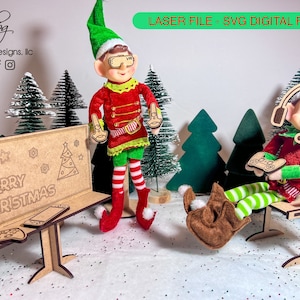 May include: Two elf figurines playing video games. The elf on the left is wearing a red and green outfit and holding a video game controller. The elf on the right is wearing a red and green outfit and a headset and holding a video game controller. The elves are sitting in front of a wooden sign that says "Merry Christmas".