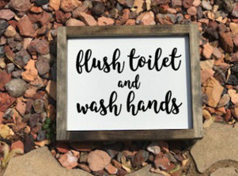 May include: White wooden sign with black text that reads "flush toilet and wash hands".