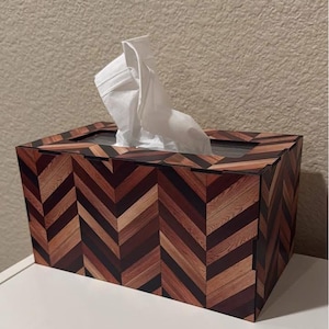 Könnte beinhalten: Ein Holz-Tischtuchbox-Bezug mit einem Chevron-Muster in Braun-, Rot- und Schwarztönen. Der Bezug hat eine transparente Plastiköffnung für die Taschentücher.
